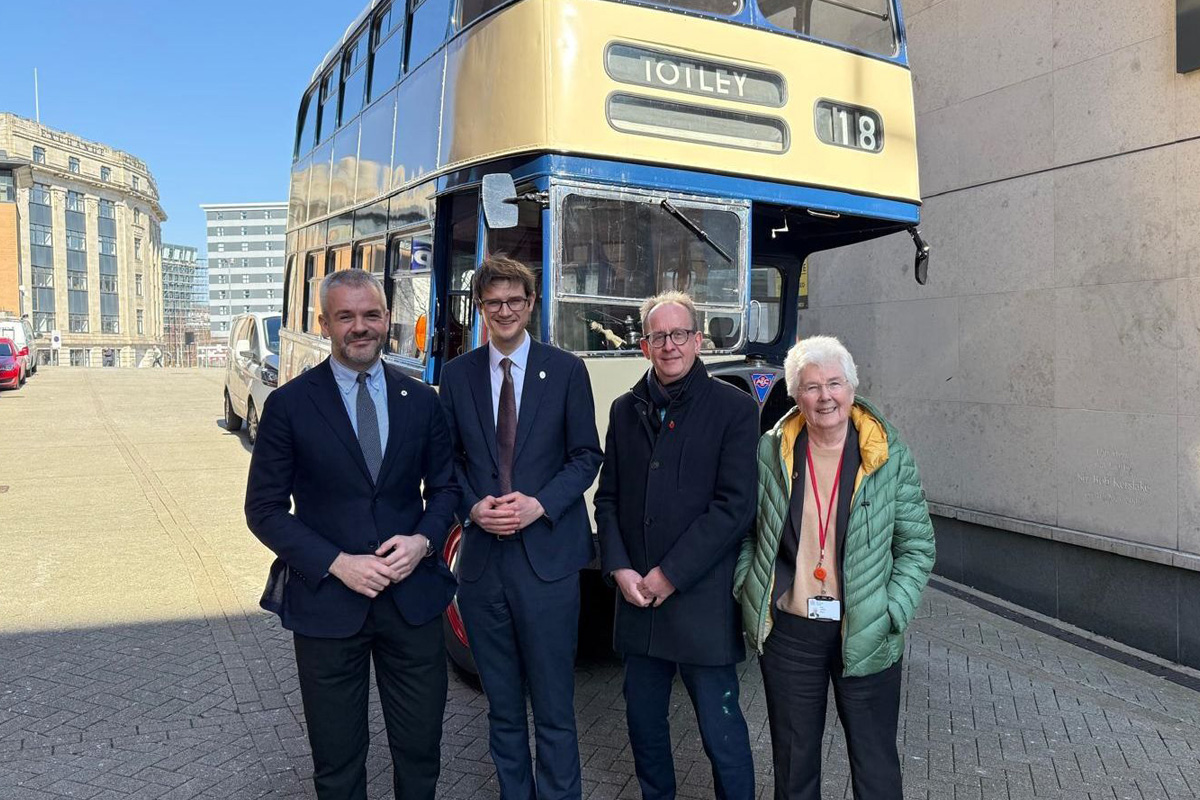 Four people stood in front of a bus