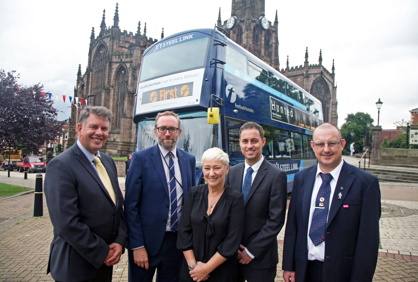 5 people stood infront of a bus.