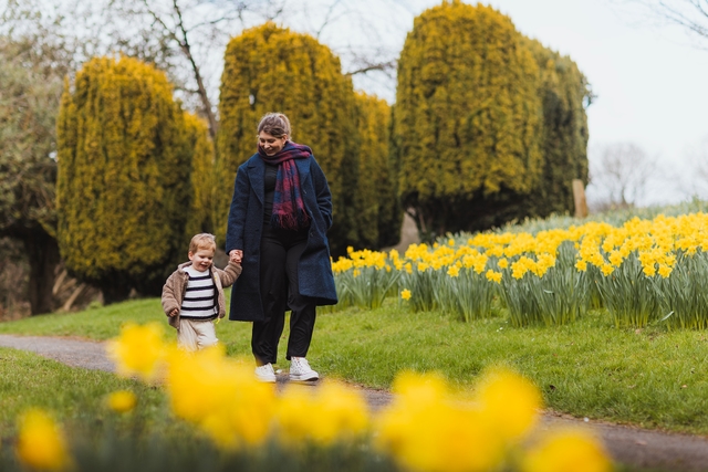 Mother and son walking next to flowers